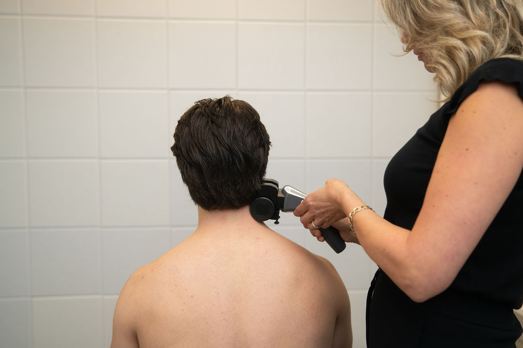Woman scanning man's neck at chiropractor's office North Vancouver