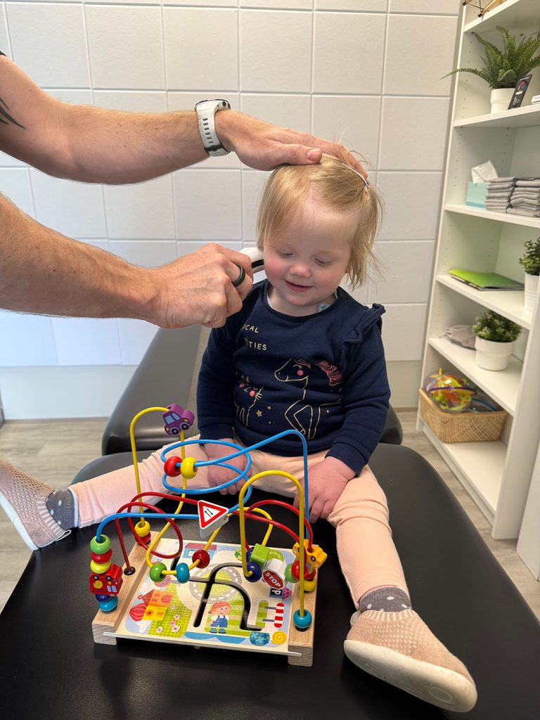 Child playing with colorful activity toy while a neurological chiropractor in North Vancouver checks for developmental milestones