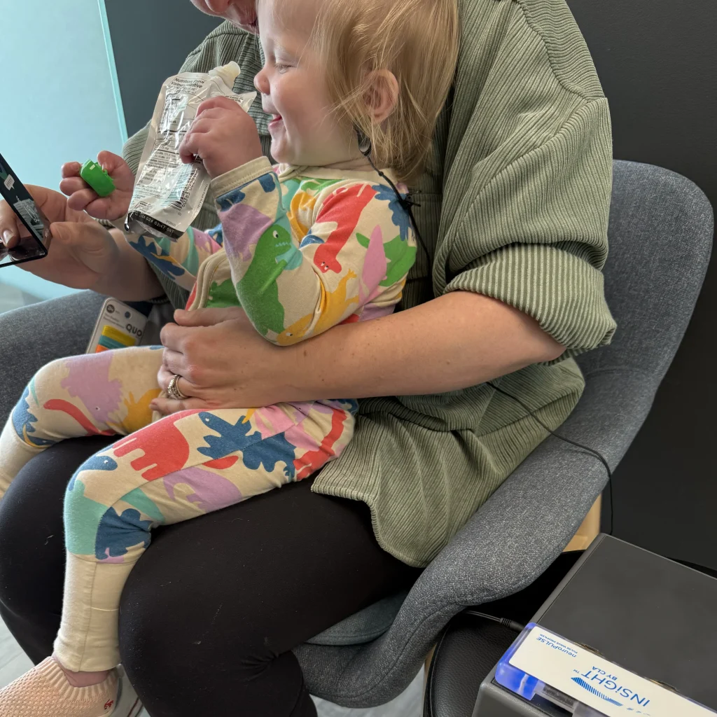 Child snacking while being held waiting for chiropractor in Lynn Valley North Vancouver