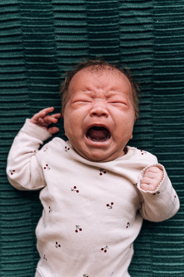 newborn baby with colic or reflux in North Vancouver cries on a green blanket